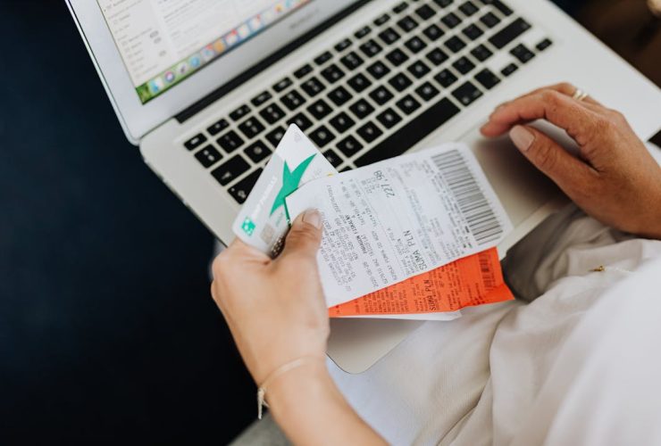 Close-up of hands holding receipts and a bank card in front of a laptop, representing online shopping and e-commerce.