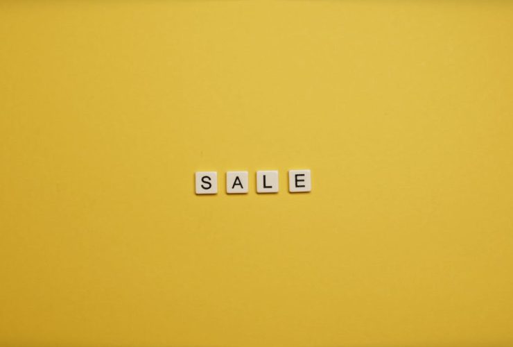 Single word 'SALE' spelled with tiles on a bright yellow background, ideal for advertising.