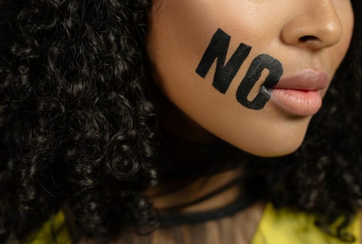 Close-up of a woman with 'No' painted on her face, conveying a powerful message.