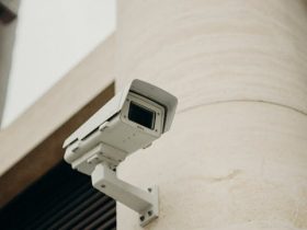 Close-up of a CCTV camera on a concrete building, symbolizing security and technology.