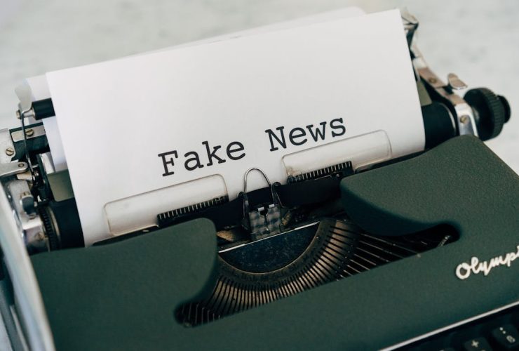 Close-up of vintage typewriter printing 'Fake News', depicting false information concepts.