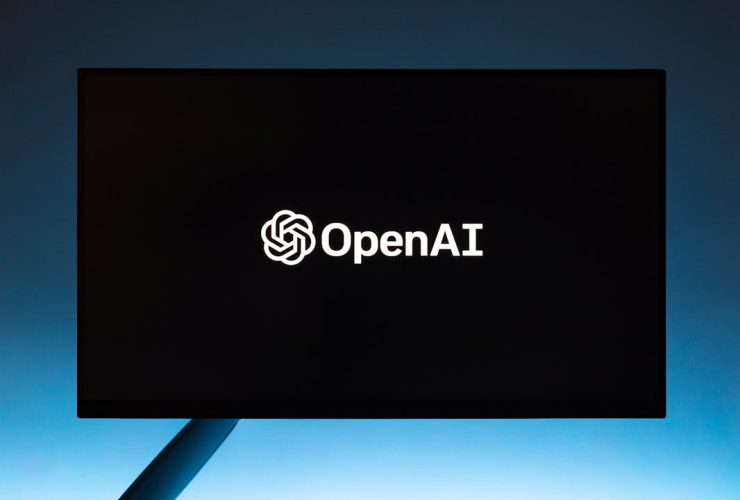 Minimalist display of OpenAI logo on a screen, set against a gradient blue background.
