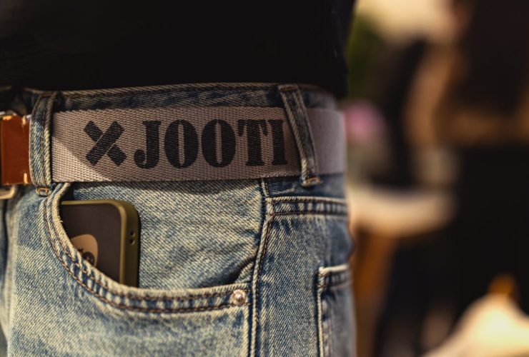 Stylish jeans with a branded belt and smartphone, captured at a Berlin fashion event.