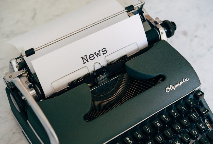 Close-up of an antique typewriter with 'News' on paper.