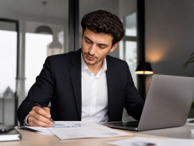 Giovane imprenditore al lavoro in ufficio con computer e documenti