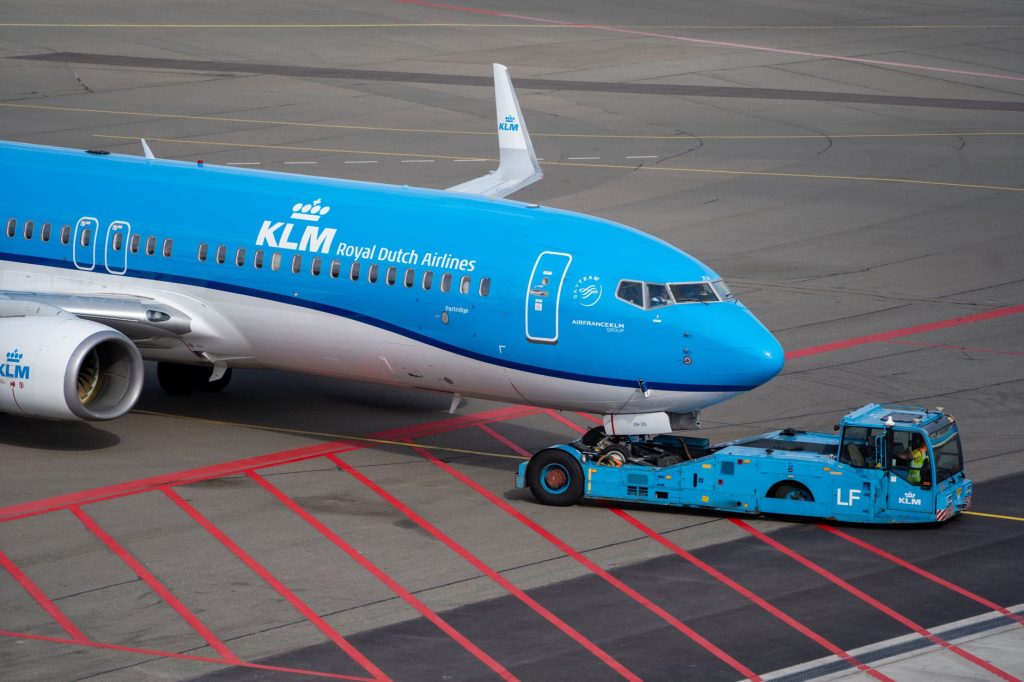 Aereo KLM sulla pista trainato da un rimorchiatore blu all'aeroporto.