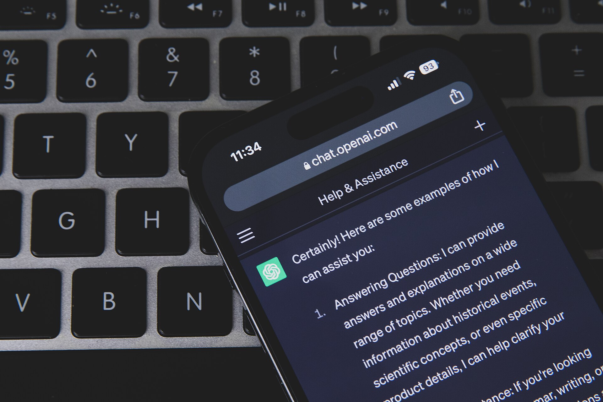Smartphone con ChatGPT appoggiato sulla tastiera di un computer