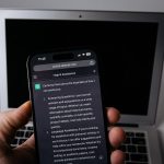 Smartphone con l'app ChatGPT accanto a un laptop
