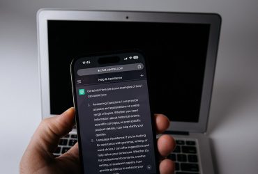 Smartphone con l'app ChatGPT accanto a un laptop