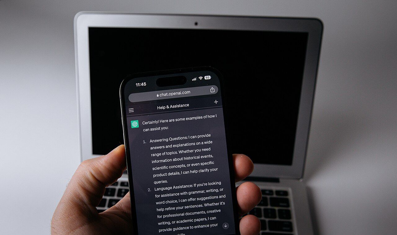 Smartphone con l'app ChatGPT accanto a un laptop