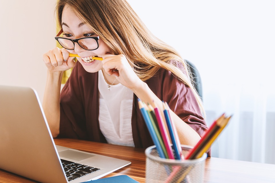 Ragazza concentrata davanti al laptop con una matita in bocca